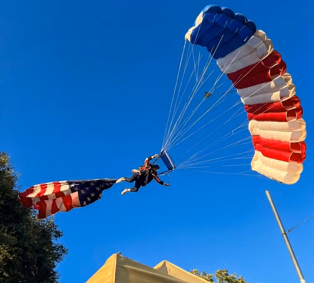 VÍDEO: Paraquedista amarrado a bandeira gigante dos EUA se enrosca em árvore e cai sobre tenda
